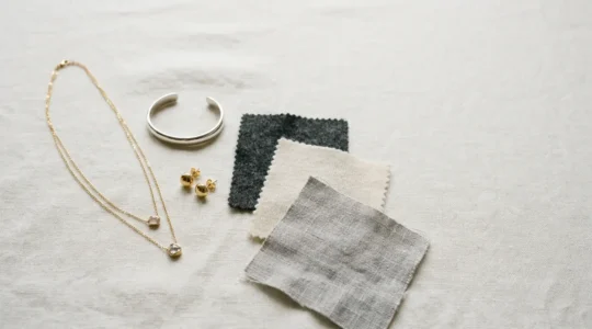 Minimalistisch angeordnete Schmuckstücke und Kleidungselemente auf neutralem Hintergrund, die das Konzept einer durchdachten Garderobe symbolisieren